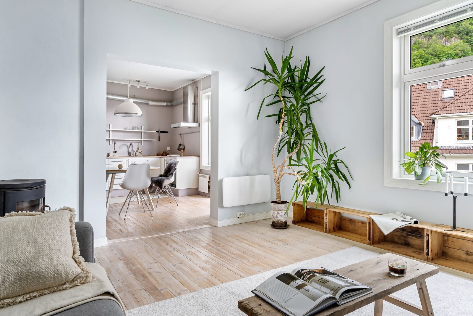 Lys, minimalistisk stue med naturlys, planter og åpen kjøkkenløsning